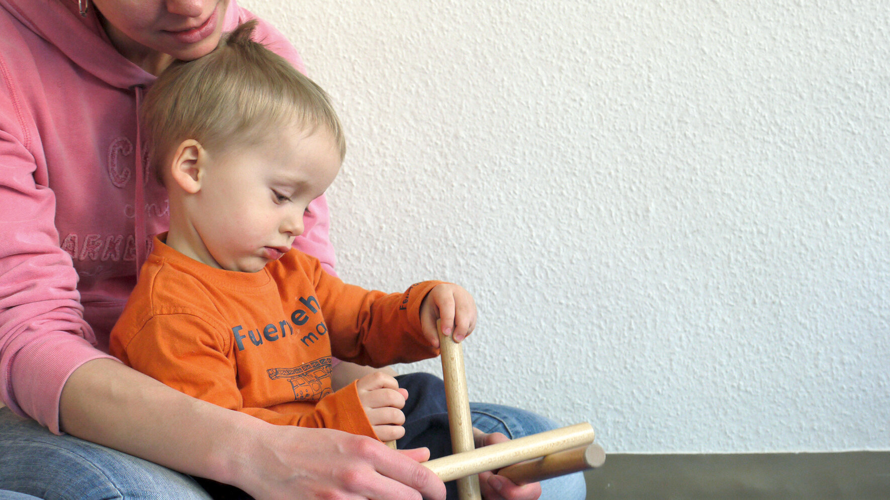 Kleiner Junge und Mutter spielen mit Klanghölzern