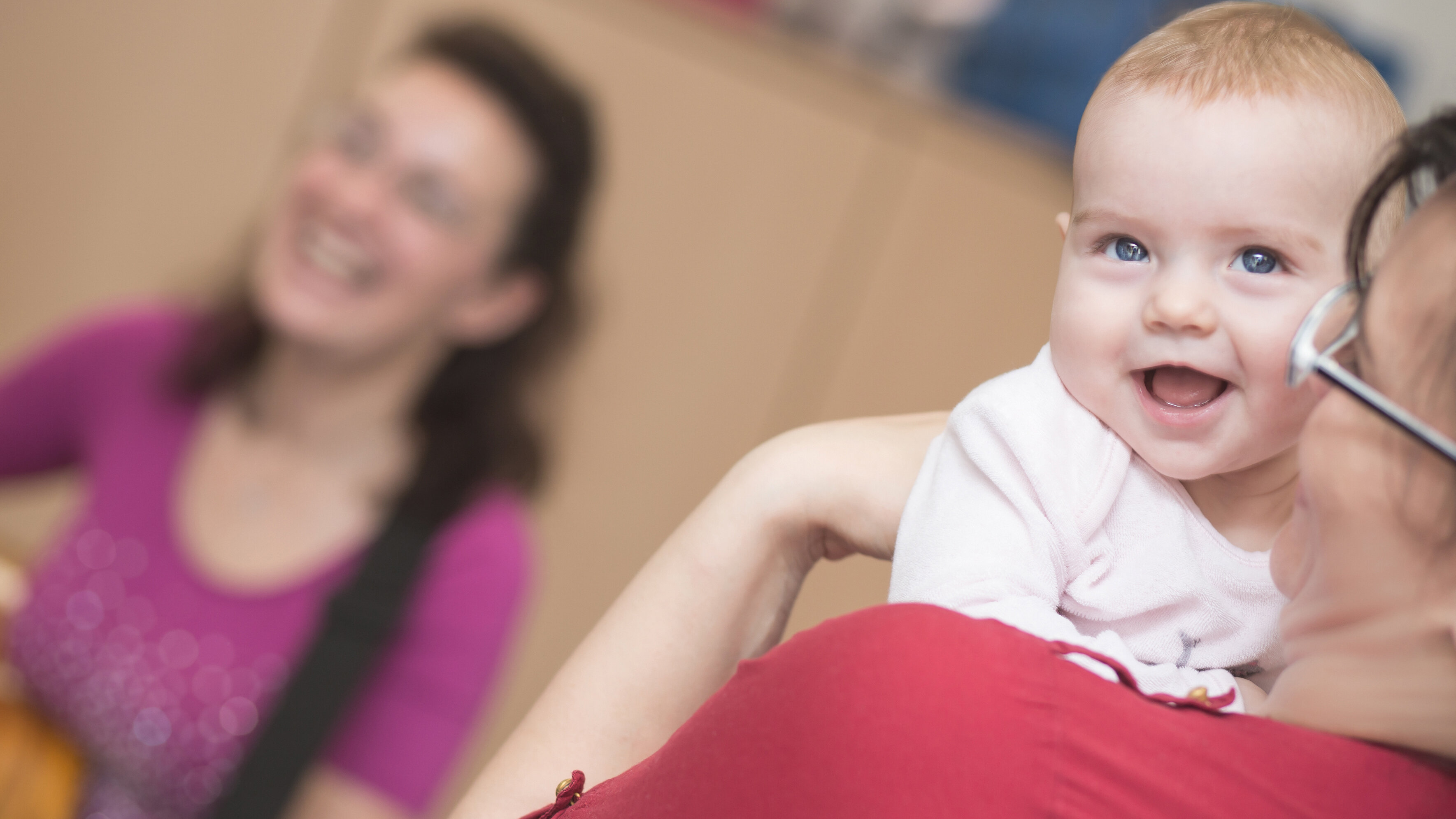 Kleines lachendes Baby auf der Schulter der Großmutter.