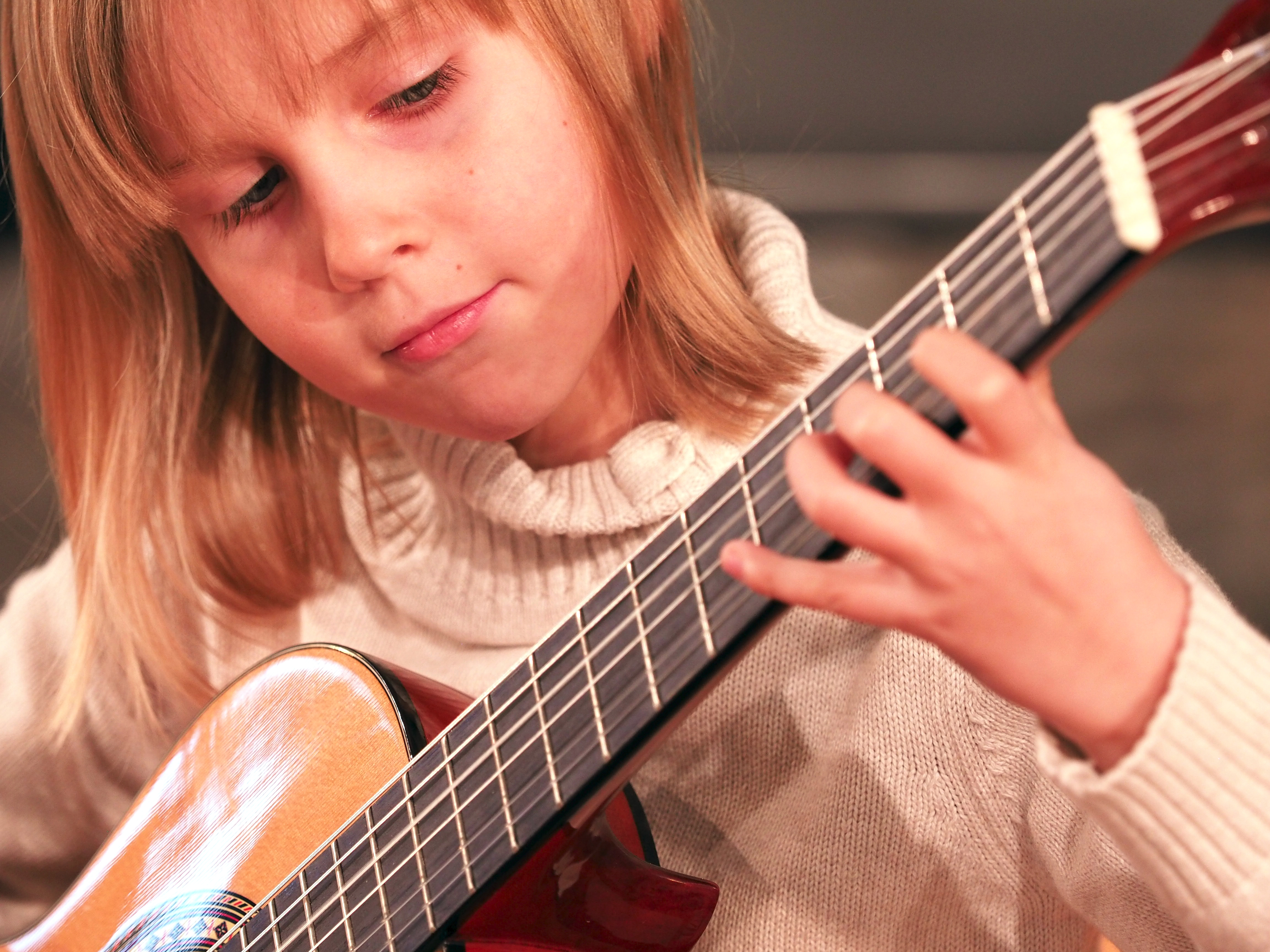 kleines Mädchen zupft ihre Gitarre