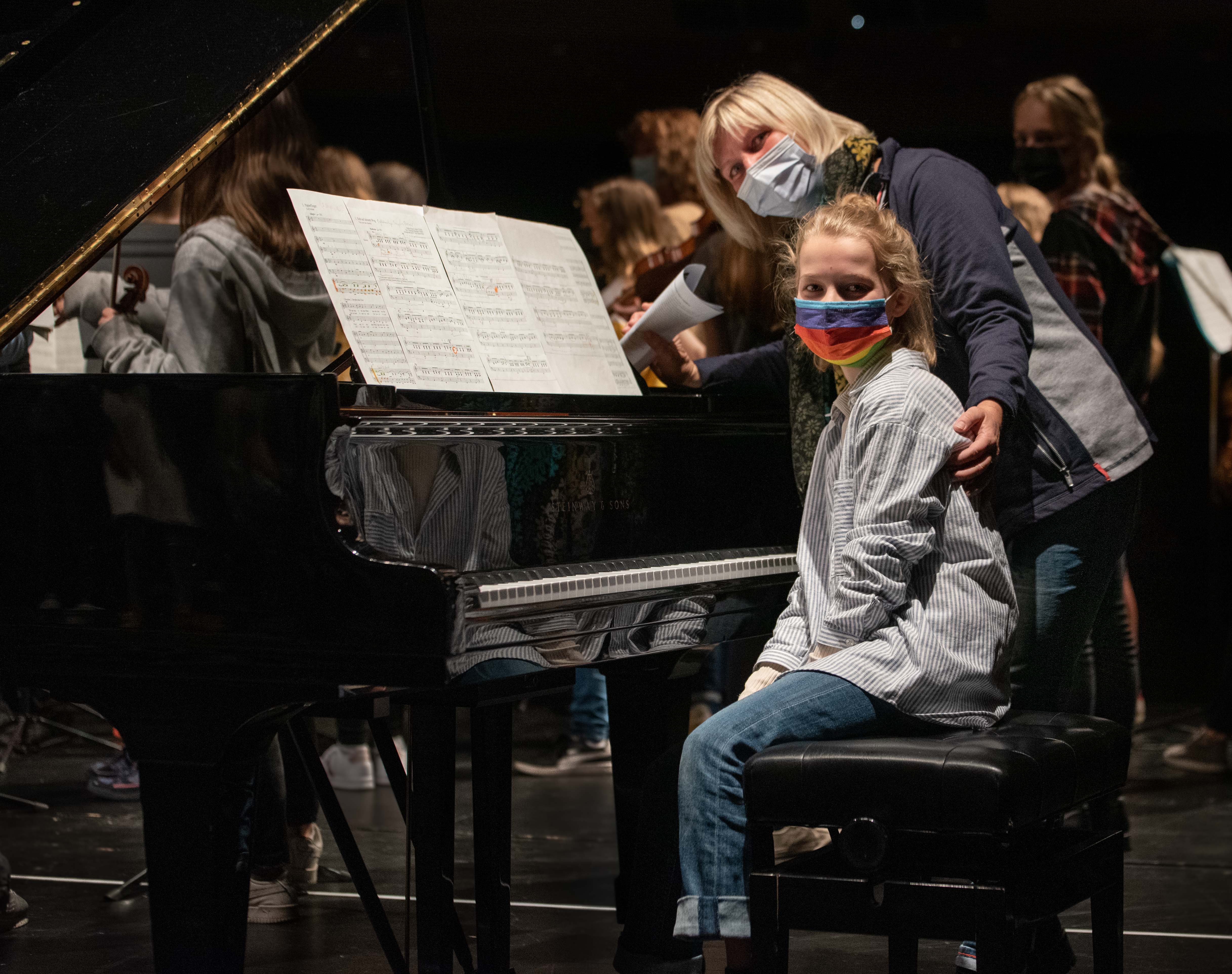 Eine Musikschullehrerin steht mit einer Schülerin vor einem Flügel