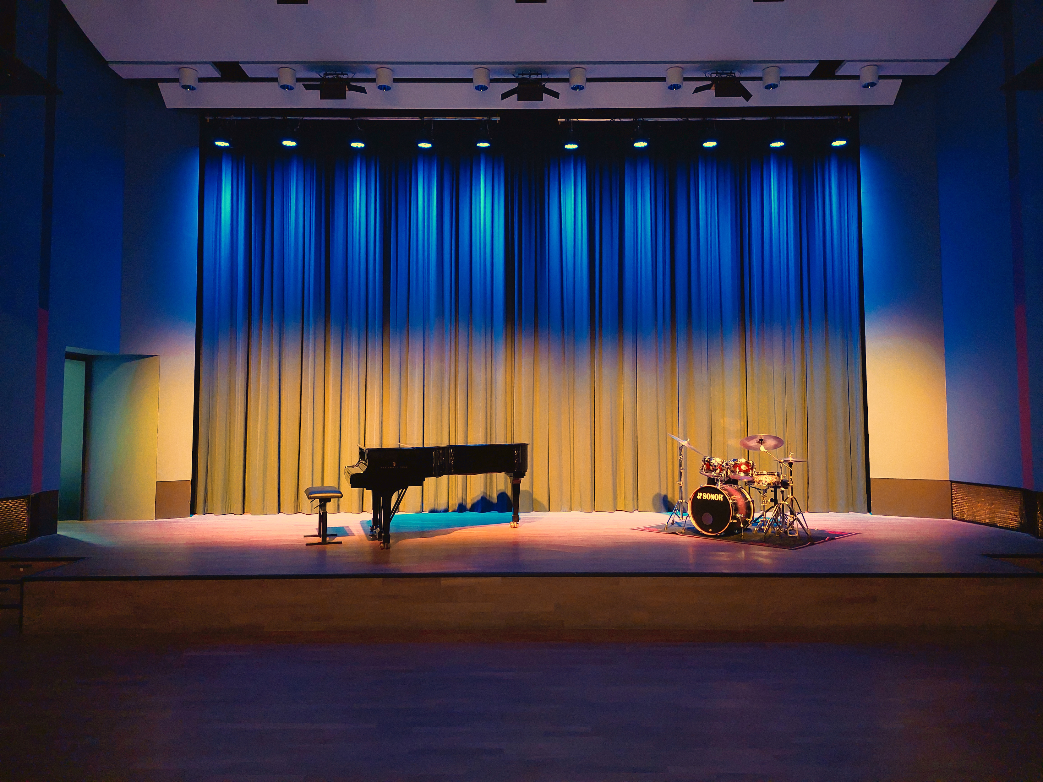 Der Vorhang im Konzertsaal ist in den Farben der ukrainischen Flagge beleuchtet, davor stehen ein Flügel und ein Schlagzeug