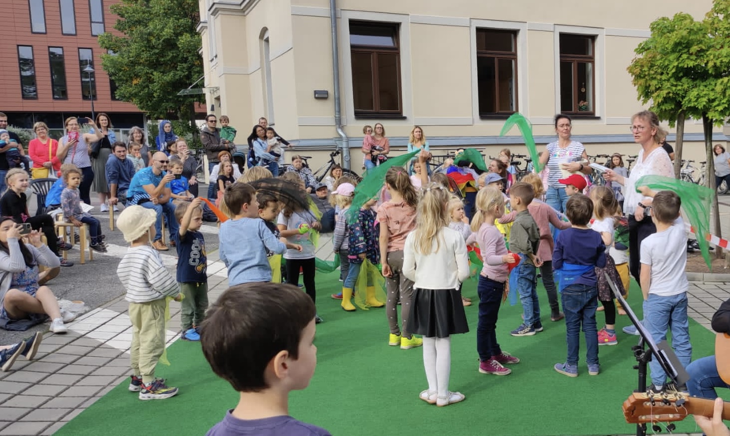 Die Kinder des Fachbereichs MFE tanzen mit grünen Tüchern