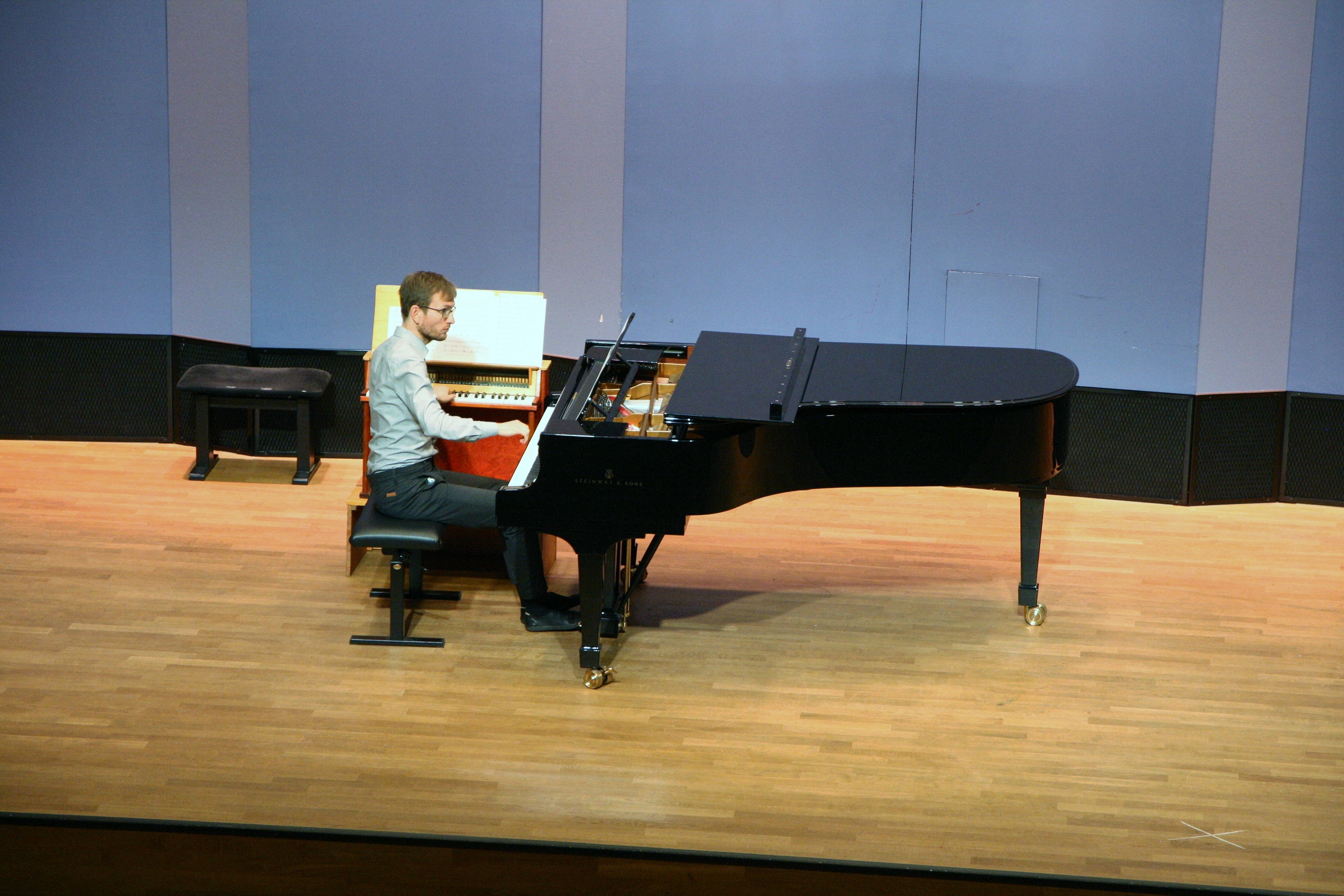 Ein Pianist spielt gleichzeitig an einem Toy Piano und einem Flügel.